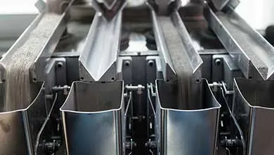 Close-up of an industrial machine dispensing granular substance from multiple metal chutes into containers.