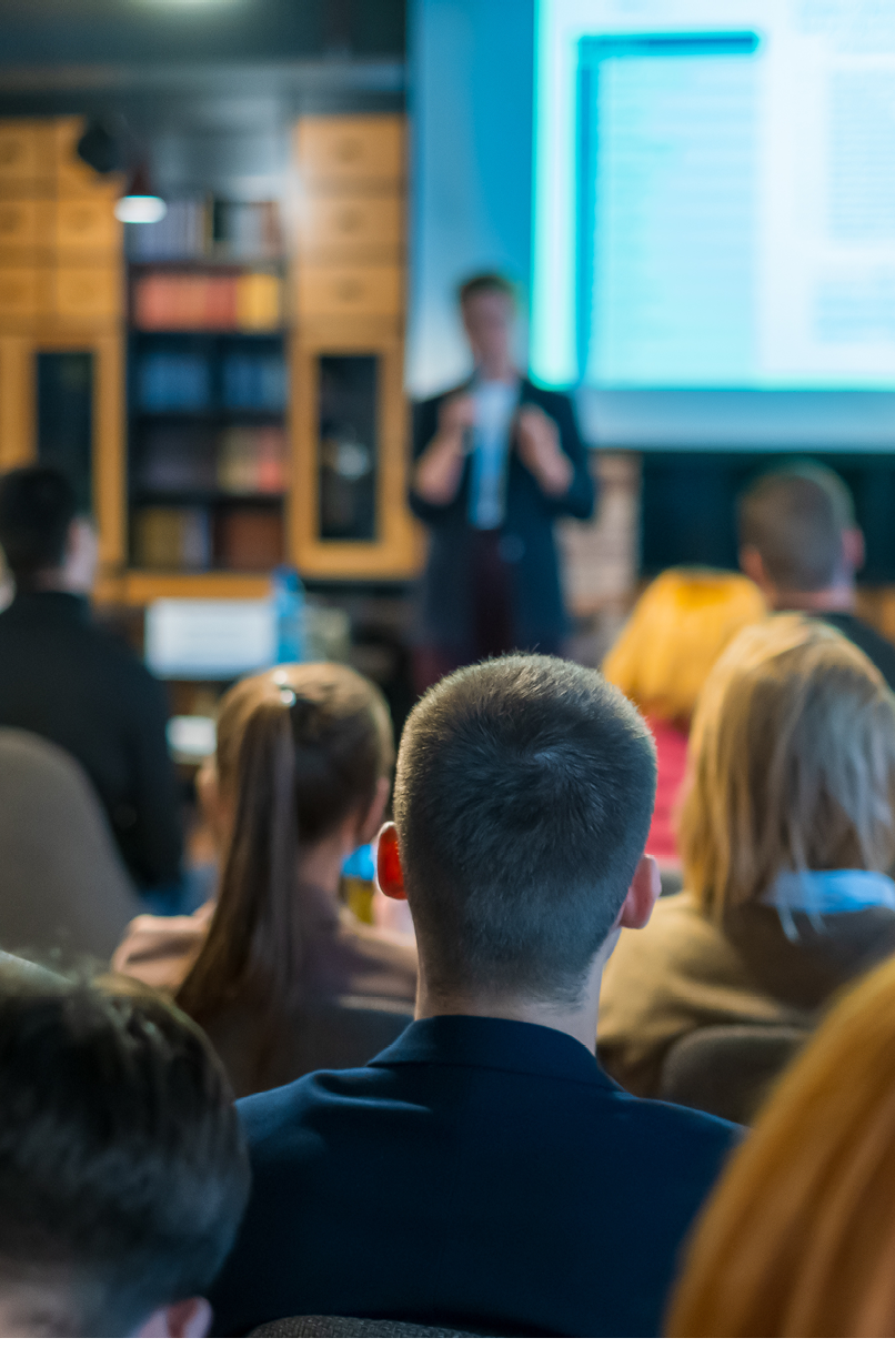 Audience listens lecturer at workshop in conference hall, rear view
